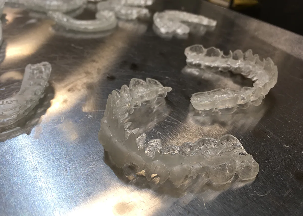 Clear 3D-printed surgical splints on a steel work surface.